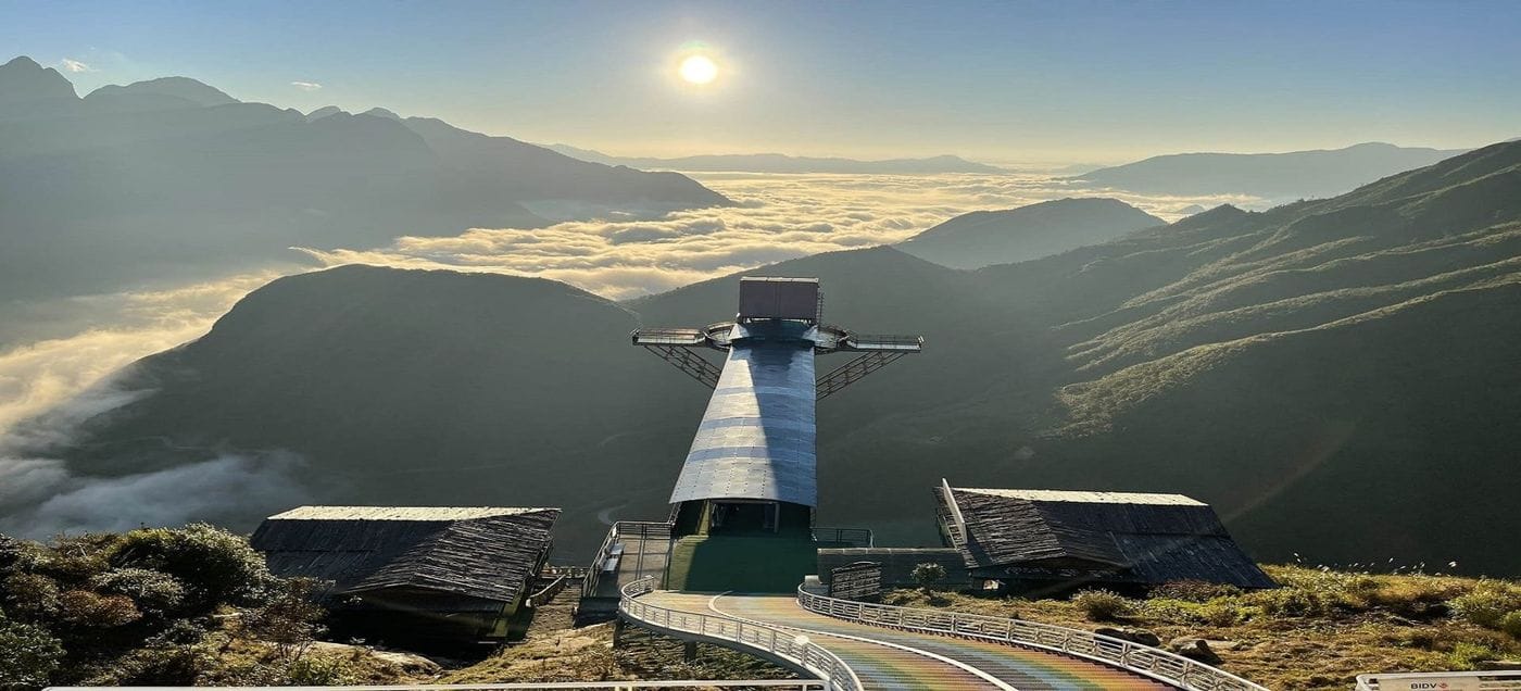 The Rồng Mây lift tower and glass bridge on the pass, with a sunlit sea of clouds behind.