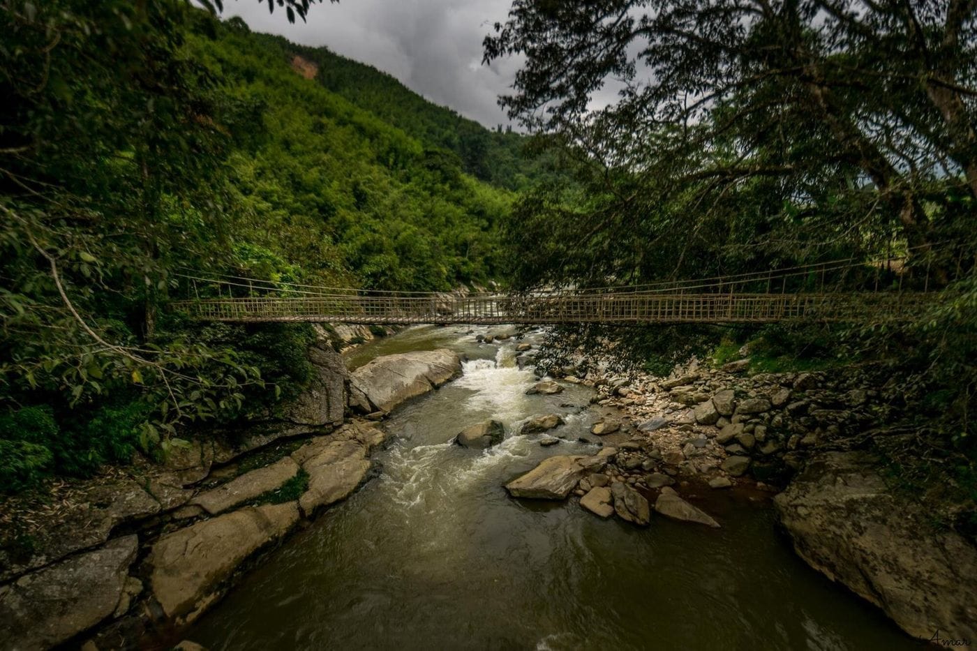 The Cau May rattan bridge spanning a rocky stream in the forest near Ta Van.