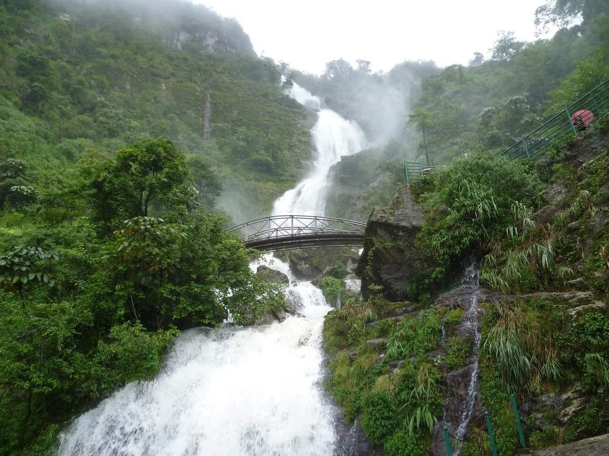 Silver Waterfall seen from its foot, white water rushing down past the small bridge between the cliffs.