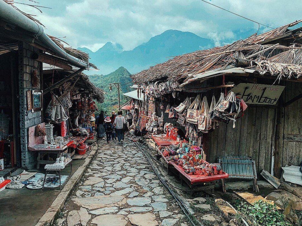 The stone-paved lane between brocade and souvenir stalls, with mountains in the distance.