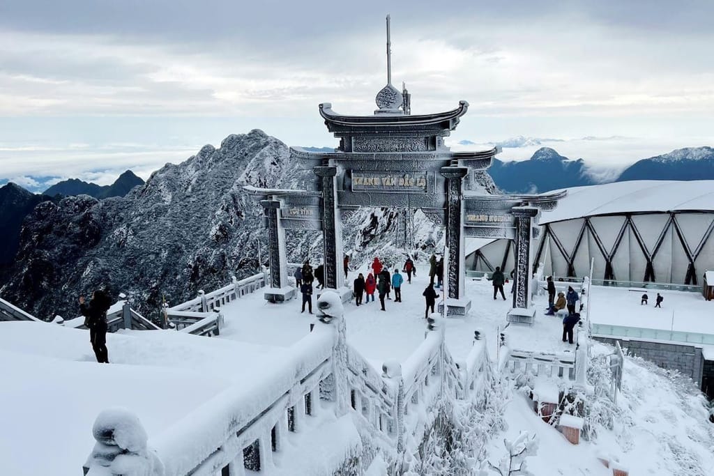 Das Tempeltor am Fansipan unter Schnee, Besucher laufen umher.