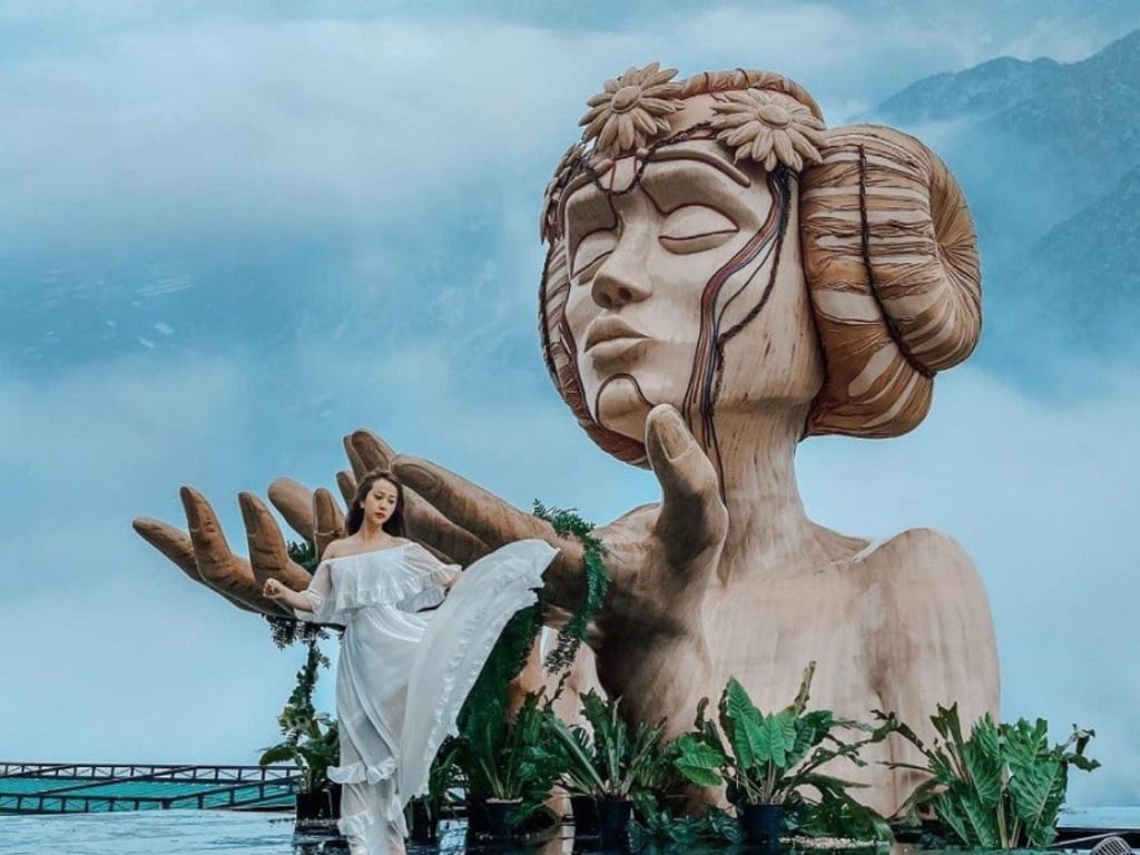 Eine Frau in Weiß posiert im Nebel an der Moana-Statue.