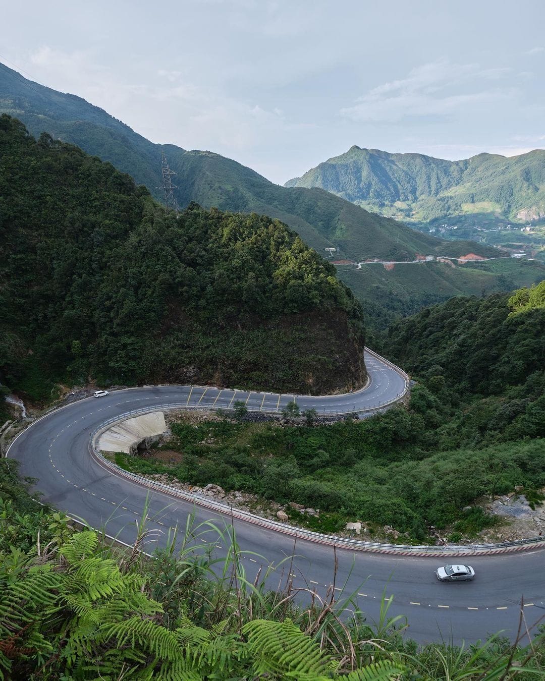 A hairpin bend on Ô Quy Hồ pass with a car taking the curve.