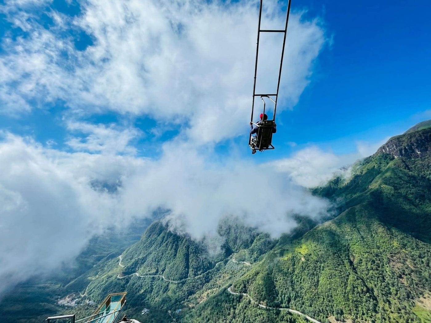 A visitor on the cliff swing hanging in the sky above clouds and the valley.
