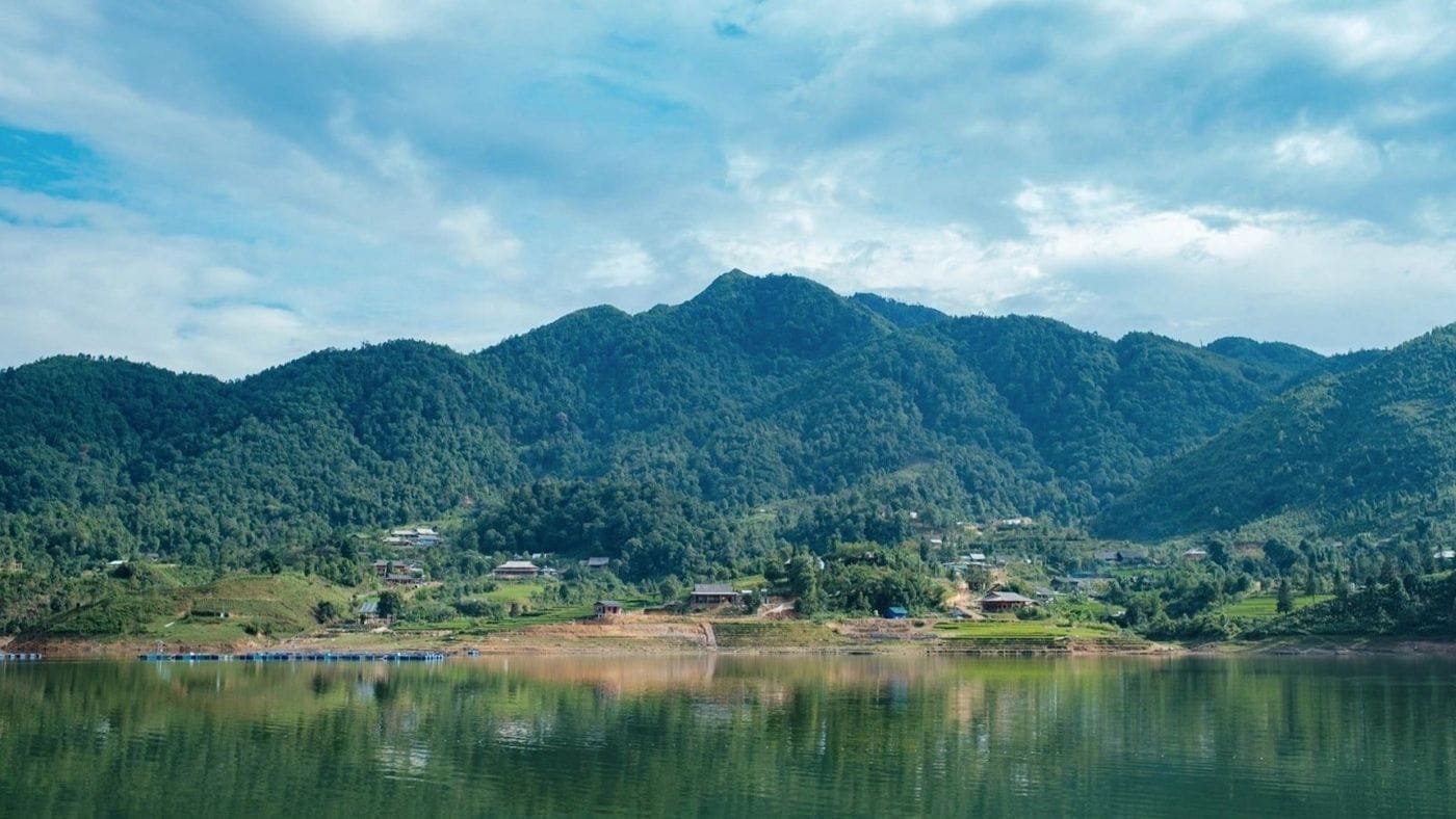 Still Seo My Ty lake mirroring the green mountains and the village on its shore.