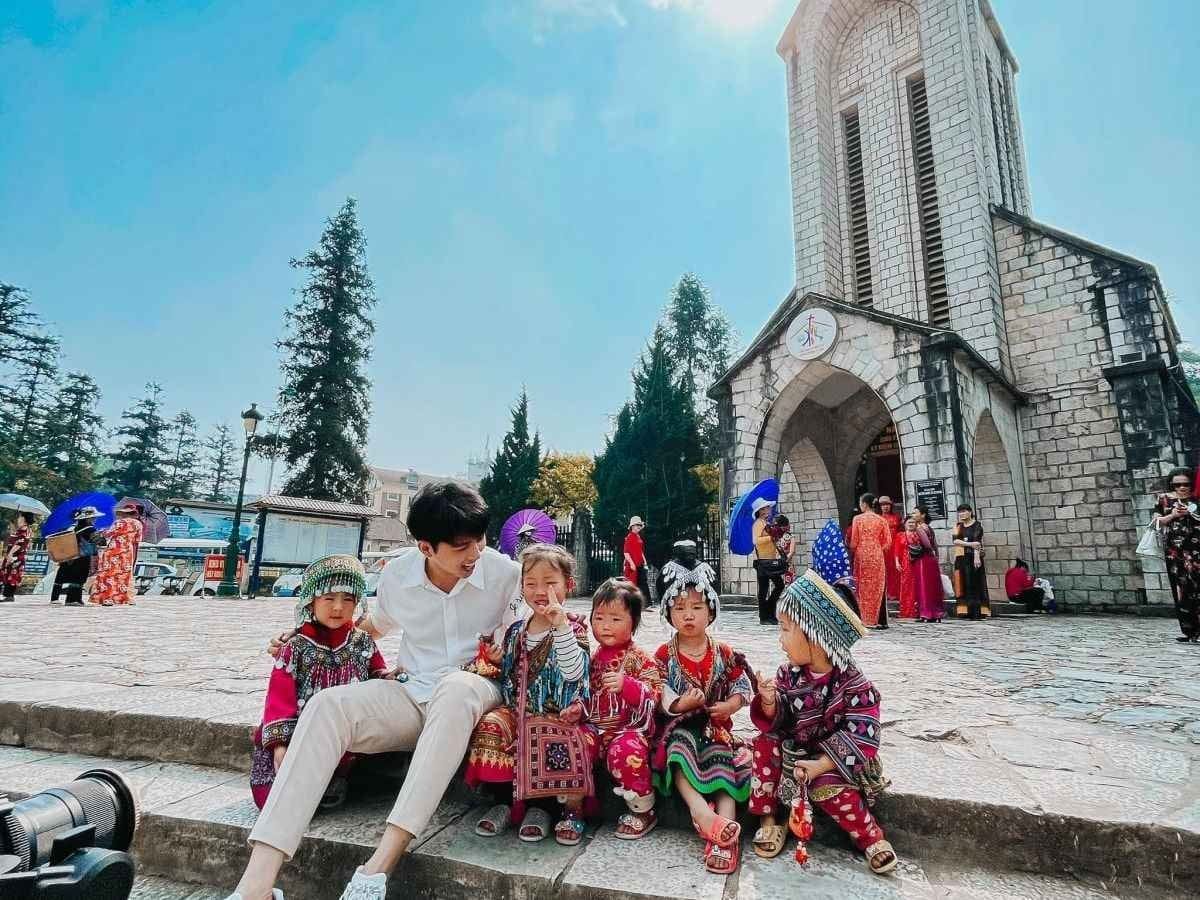 돌 성당 앞 돌계단에 전통 의상을 입은 아이들과 함께 앉아 있는 여행자.